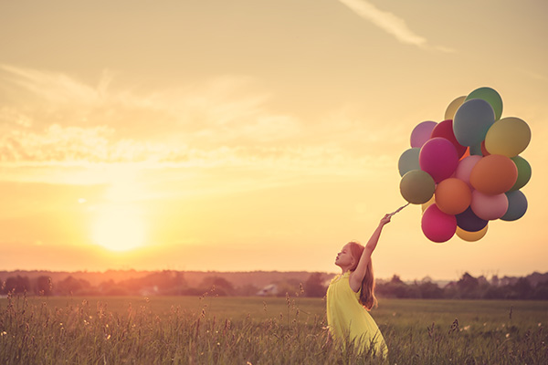 Petite fille avec des ballons dans un champ